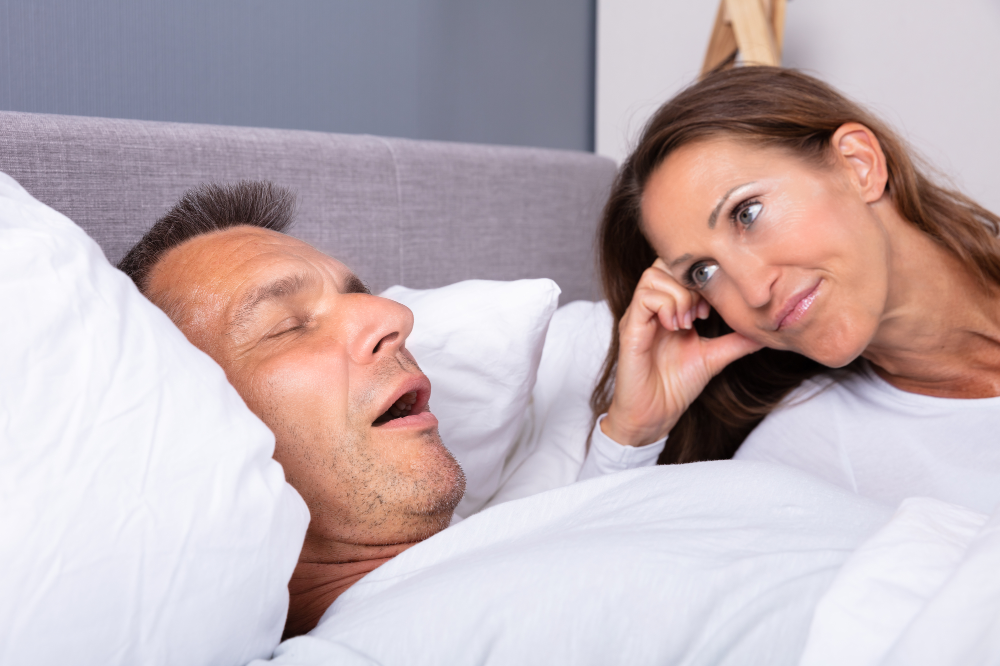 man snoring in bed with woman watching
